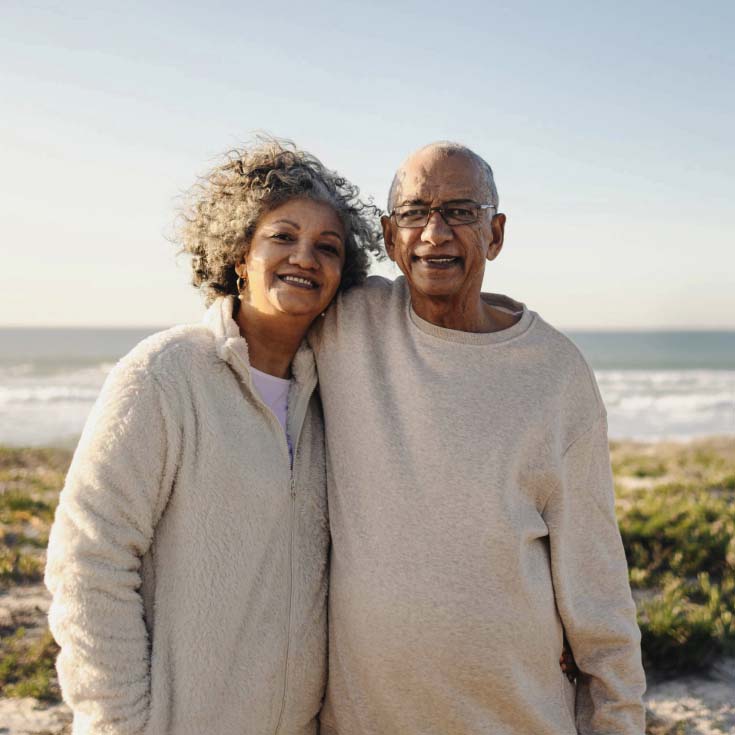 A mature couple smiles on a beach